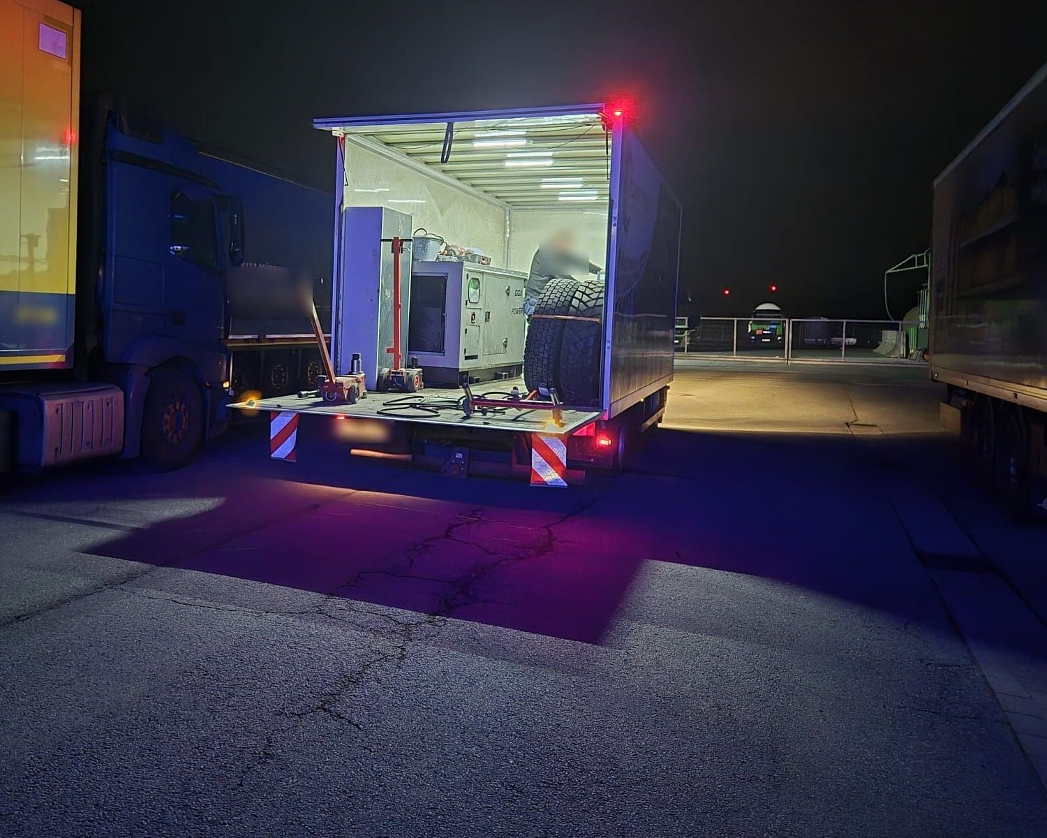 Nachteinsatz: der RuhrTruck-Servicewagen mit geöffnetem Aufbau, Reifen und Werkzeug neben einem liegengebliebenen Lkw